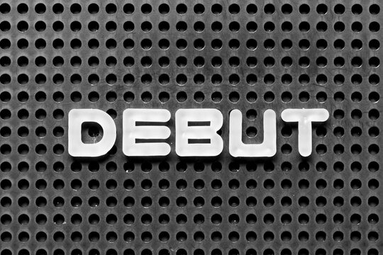 White alphabet letter in word debut on black pegboard background