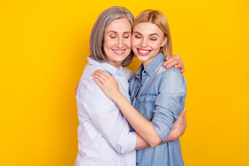 Photo portrait of dreamy happy granddaughter embracing her smiling granny isolated bright yellow color background