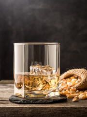 A glass of classic corn whiskey (bourbon) on a wooden table. Vertical photo.