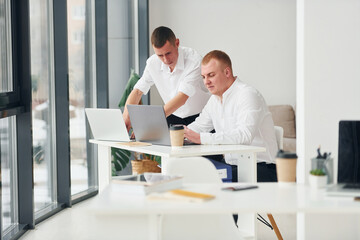 Two male office workers in formal clothes working together
