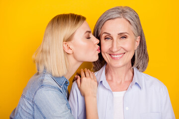 Photo portrait of daughter kissing her lovely mum smiling isolated bright yellow color background