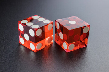 Two red dice on a black background with light. The result is 