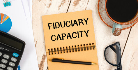 Notebook with text Fiduciary Capacity near office supplies.
