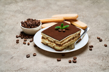 Portion of Traditional Italian Tiramisu dessert and coffee beans on grey concrete background