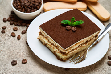 Portion of Traditional Italian Tiramisu dessert and coffee beans on grey concrete background