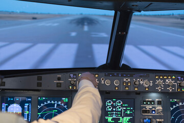 Front of the cockpit of a commercial flight simulator and view of an airport take-off runway