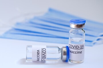 Creative ideas of vaccination concept. Top view of medical masks and vaccine vial glass bottles for vaccination against COVID-19. Coronavirus pandemic. Copy space. 