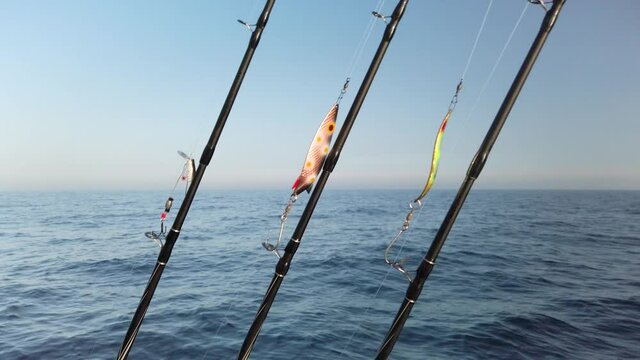 Three fishing rods hooked up with spinners, ready for fishing. The rods are lined up in a row on a small fishing boat. It is a beautiful sunny spring day. 1080p slow motion