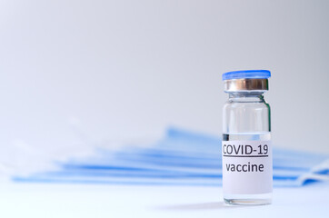 Creative ideas of vaccination concept. Top view of medical masks and vaccine vial glass bottles for vaccination against COVID-19. Coronavirus pandemic. Copy space. 