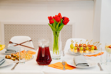 vase with a bouquet of red tulips on the festive table. serving the table with appetizers, canapes, salads in jars. Catering. restaurant business.