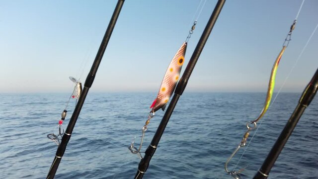 Three fishing rods hooked up with spinners, ready for fishing. The rods are lined up in a row on a small fishing boat. It is a beautiful sunny spring day.