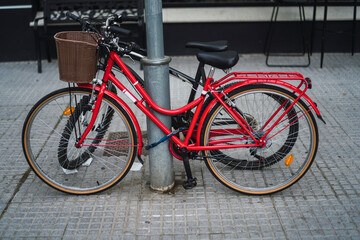 Fototapeta na wymiar Bicicleta roja atada a un poste junto a otra bicicleta negra