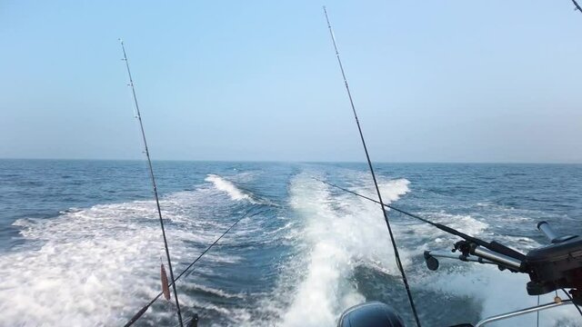 Fast fishing boat creating splashing waves at sea. Boat sail fast over ocean, water sprays when it hit waves. Fishing rods are lined up. It&rsquo;s a beautiful spring day at &Oslash;resund, Denmark. Real time 1080