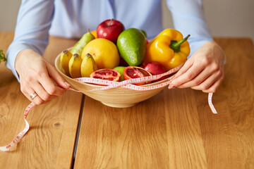 Close up of hand nutritionist, dietitian measuring bowl with healthy vegetables and fruits