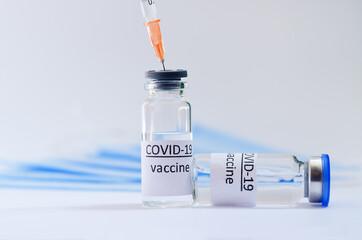 Creative ideas of vaccination concept. Top view of syringe with medical masks and vaccine vial glass bottles for vaccination against COVID-19. Coronavirus pandemic. Copy space. 