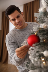 Fototapeta na wymiar Handsome man decorating Christmas tree at home