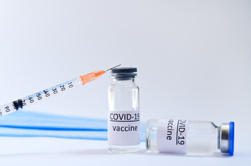Creative ideas of vaccination concept. Top view of syringe with medical masks and vaccine vial glass bottles for vaccination against COVID-19. Coronavirus pandemic. Copy space. 