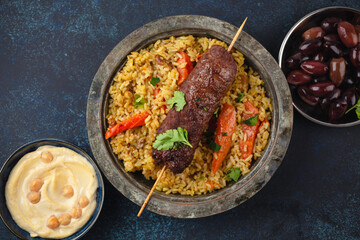 Traditional Middle Eastern meat Kebab with rice in rustic metal plate on blue rustic background top view. Arab meal for lunch or dinner, Middle Eastern cuisine 
