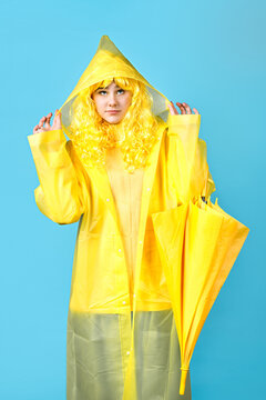 girl teenager in a yellow raincoat with an umbrella. turquoise background