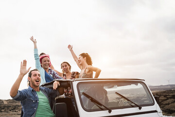Young people having fun traveling together in convertible 4x4 car during summer vacation - Soft...