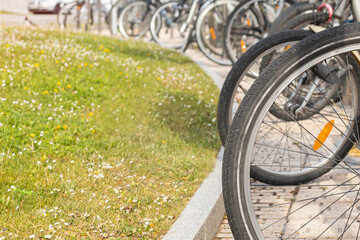 Fototapeta premium detail of bicycle wheels parked in a reserved place in the city for citizens near stores with copy space and selective focus