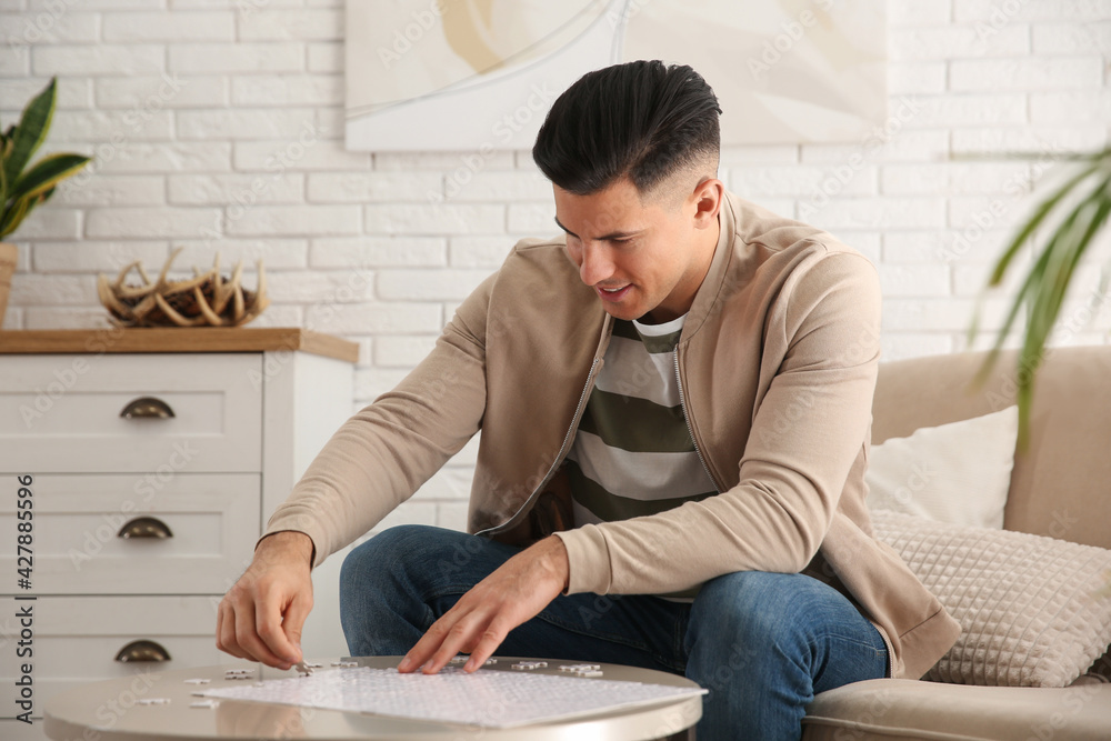 Poster Man playing with puzzles at table in living room