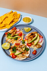 Tacos with crispy fish, avocado, guacamole sauce, nachos chips and lime. Mexican cuisine - 427885553
