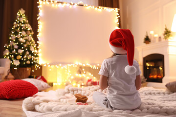 Little girl watching movie using video projector at home. Cozy Christmas atmosphere