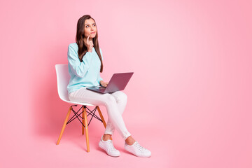 Full size profile portrait of thinking serious person finger on chin computer on knees isolated on pink color background