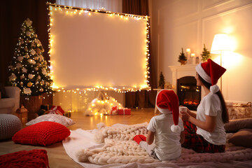 Mother and daughter watching movie using video projector at home. Cozy Christmas atmosphere