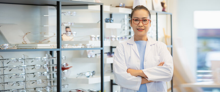 portrait of asian women middle age opticians optometrists wear glasses and uniform crossed arms standing in optical shop. image banner.