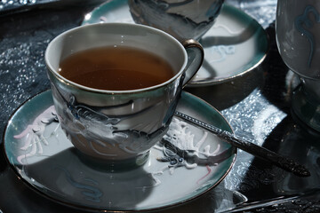 A retro luxurious porcelain cup of tea and a teapot over a silver tray