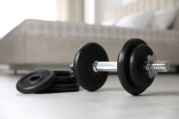 Fototapeta na wymiar Steel dumbbell and weight plates on floor indoors. Fitness at home