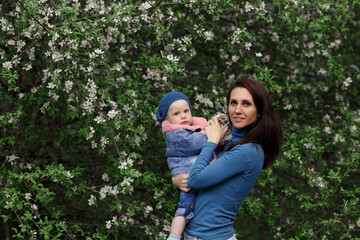 Fototapeta premium a beautiful brunette girl in blue clothes is holding a little girl in a blue beret and a blue fur coat