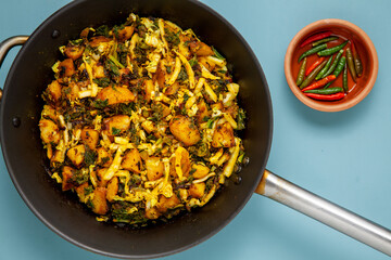 Fried dish with potatoes, cabbage and kale leaves. Indian vegetarian cuisine Subji meal.