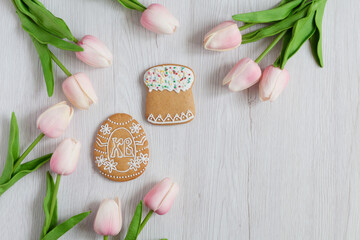 Homemade Gingerbreads in the form of egg, cake, candle on Easter with pink tulips on wooden background. Space for text