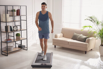 Fototapeta na wymiar Sporty man training on walking treadmill at home