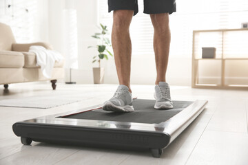 Obraz premium Sporty man training on walking treadmill at home, closeup