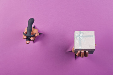 Black silicone sex toy on pink background in female hands . Erotic toy for fun. Sex gadget and device for masturbation. Space for the text. The concept of a sex shop. Dildo, anal butt plugs.