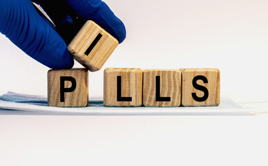 Text PILLS made from wooden cubes. Hands in a blue glove.