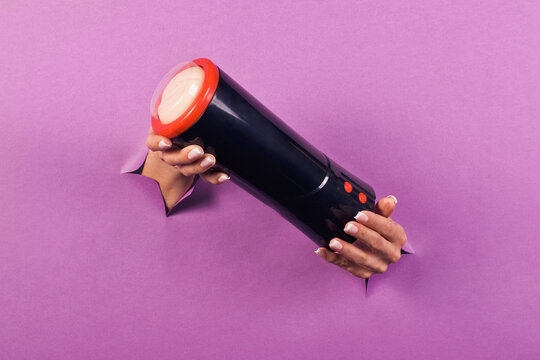 A masturbator for men is a sex toy on a pink background in the hands of a woman . Erotic toy for fun. Sex gadget and device for masturbation. Space for the text. The concept of a sex shop.