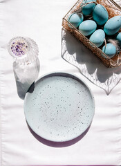 Blue plate with Easter eggs and a crystal class on top view, flat lay, add your own text, and mock up.