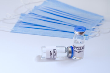 Creative ideas of vaccination concept. Top view of medical masks and vaccine vial glass bottles for vaccination against COVID-19. Coronavirus pandemic. Copy space. 