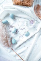 Light Blue easter eggs on a white background with lifestyle elements such as pampas grass, flowers and silk cloth
