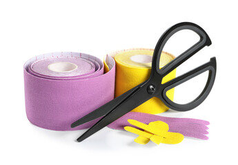 Scissors, bright kinesio tape rolls and pieces on white background