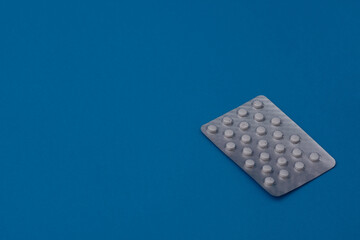 Tablets pills in a blister on a blue background. copy space