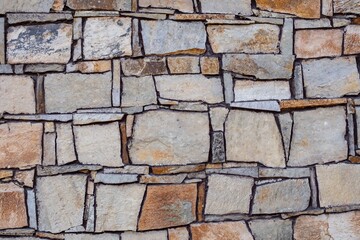 Obraz premium Brown beige grey bricks wall as abstract colorful material pattern. Architectural ornaments background, rocks and stones arranged in rows. Color combination of warm orange gamma of pastel ground tones