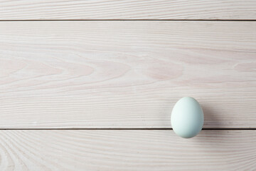 A blue egg in natural color on white wooden table.