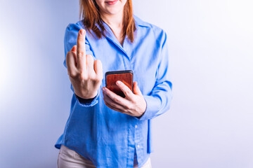 Unrecognizable woman holding a smart phone sticking out a finger at camera