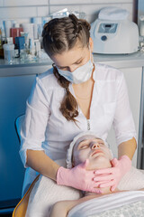Professional beautician makes a facial massage to a woman.